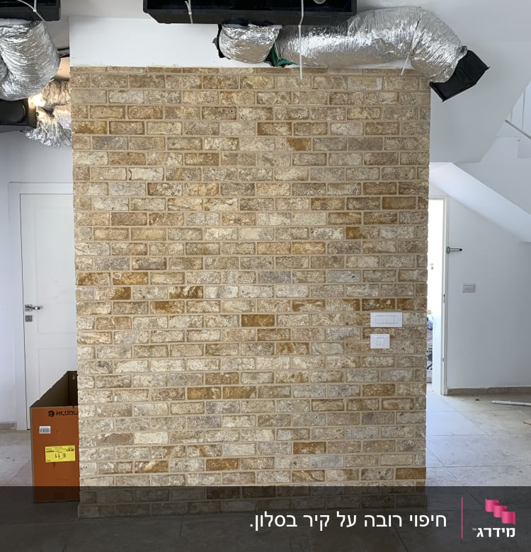 קיר לבנים, צינורות מיזוג, נורה חשופה, קופסת קרטון